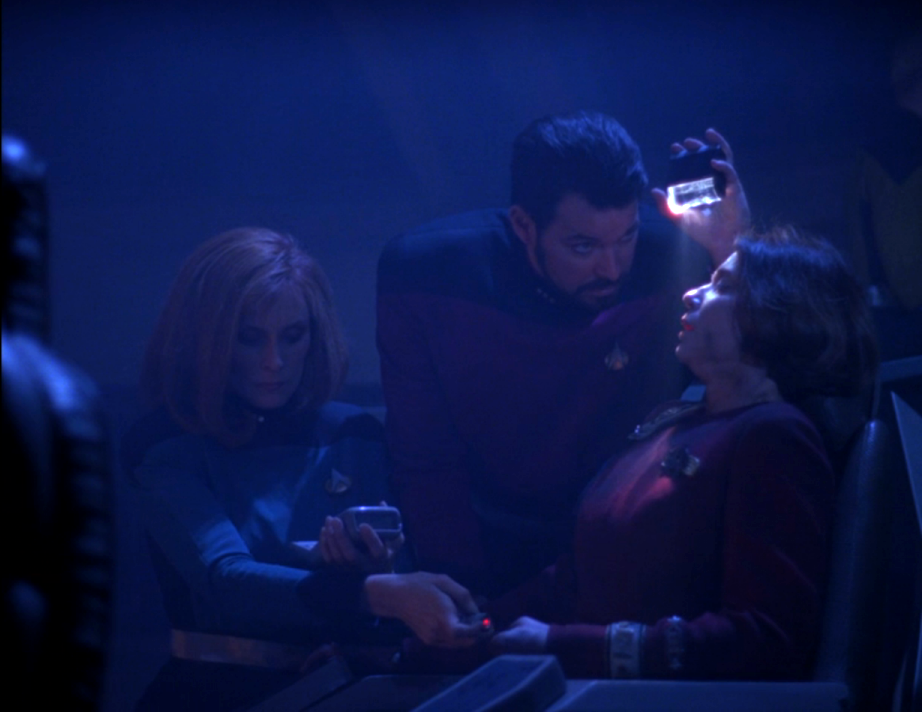 Riker and Crusher attending to an injured Captain Garrett