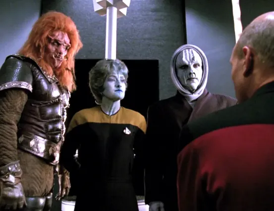 Picard speaking with three aliens in their shared holding cell