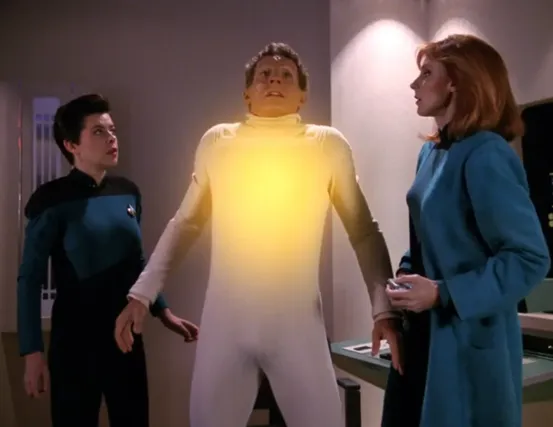 Dr. Crusher watches as a bright yellow glow emanates from her patient's chest