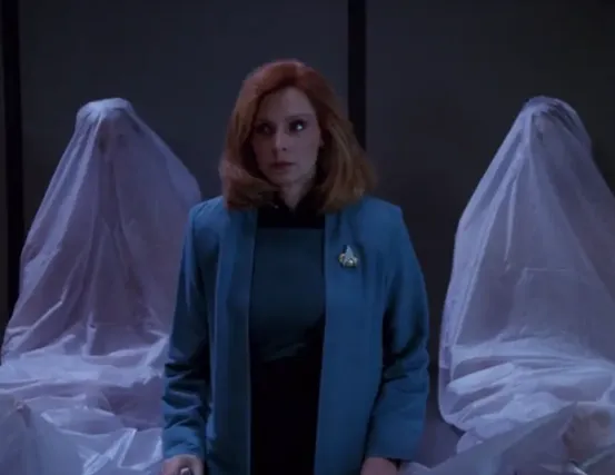 Dr. Crusher surrounded by several corpses that are sitting upright on their tables