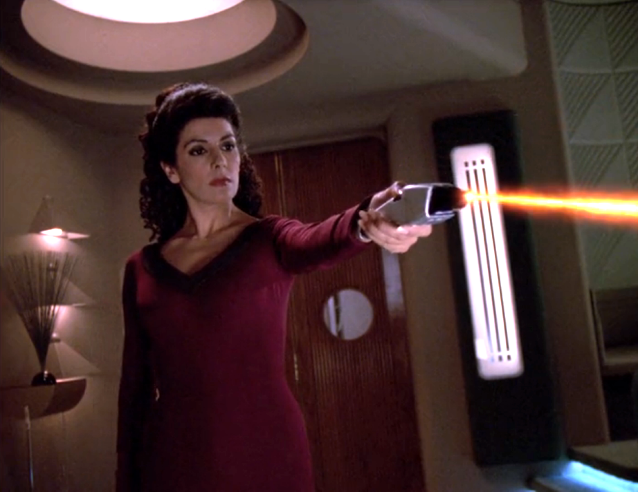 Deanna Troi firing a phaser in Ten Forward