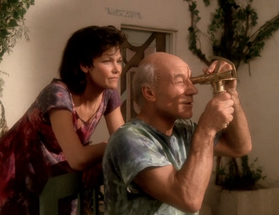 Picard looking through a small telescope while a dark-haired woman watches