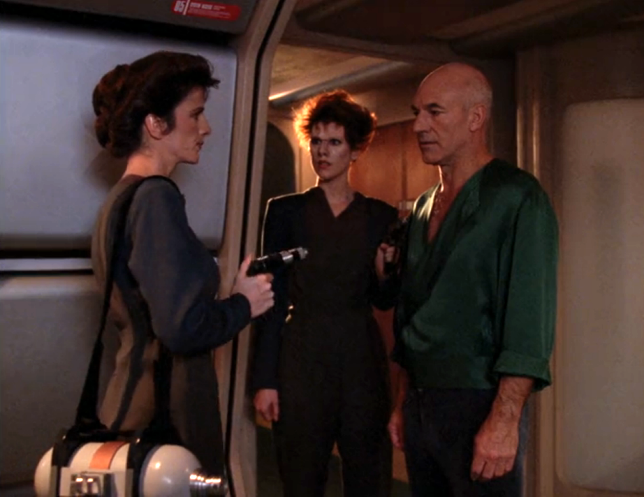 Picard, in casual clothing, being held at gunpoint by two women