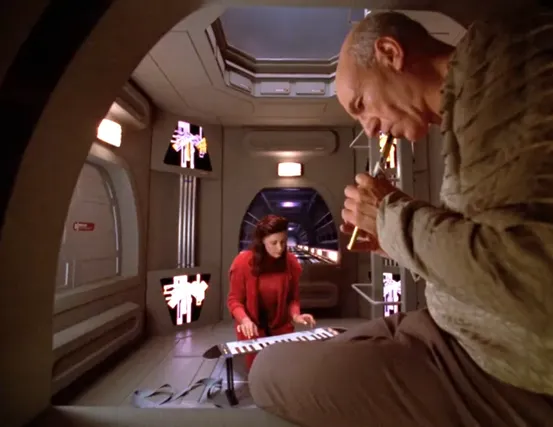 Picard playing the flute and Nella playing piano in the Jeffries tube