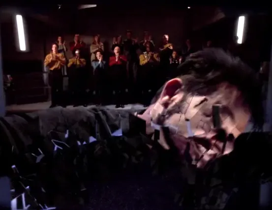 An audience giving a standing ovation as Riker literally shatters into pieces