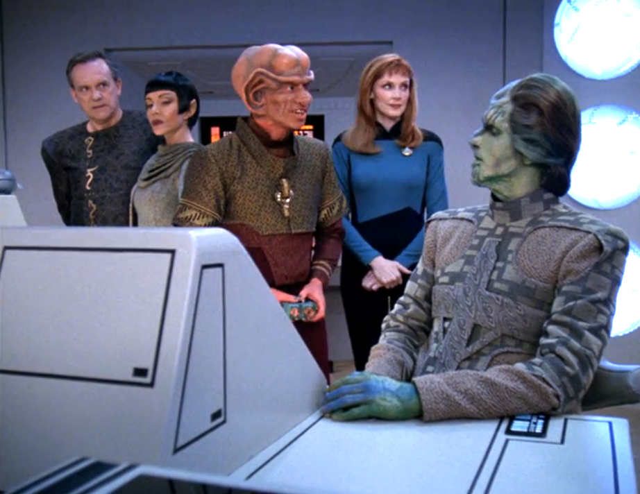 Dr. Crusher facilitating a meeting among several alien scientists