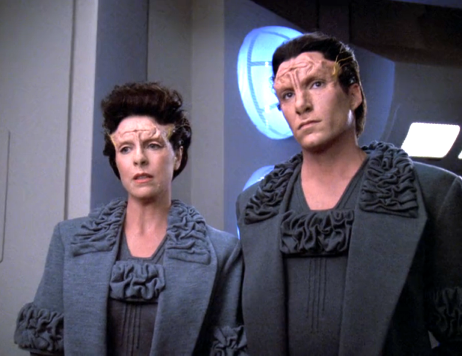 An alien brother and sister wearing matching grey robes