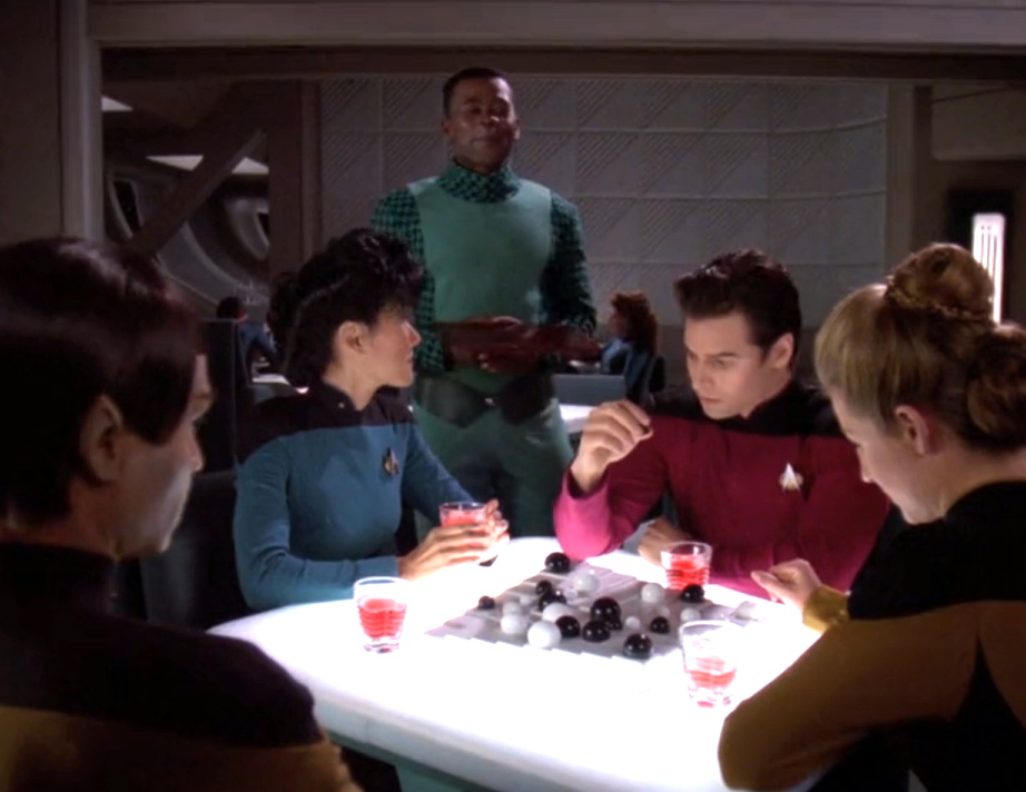 Nurse Ogawa and several other low-ranking members of the crew sitting around a table in Ten Forward