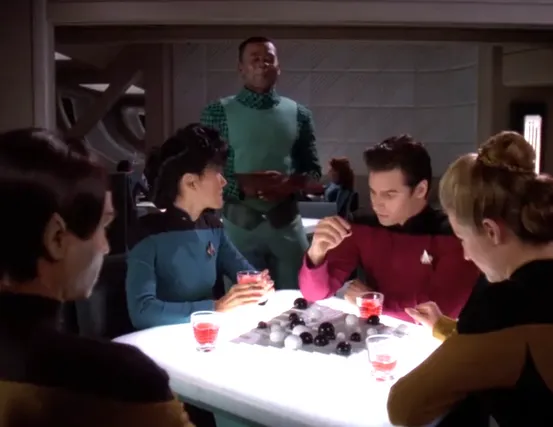 Nurse Ogawa and several other low-ranking members of the crew sitting around a table in Ten Forward