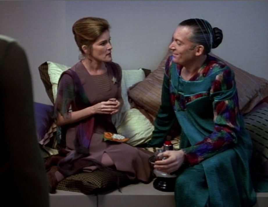 Captain Janeway in casual clothing sitting with a man having food and drink