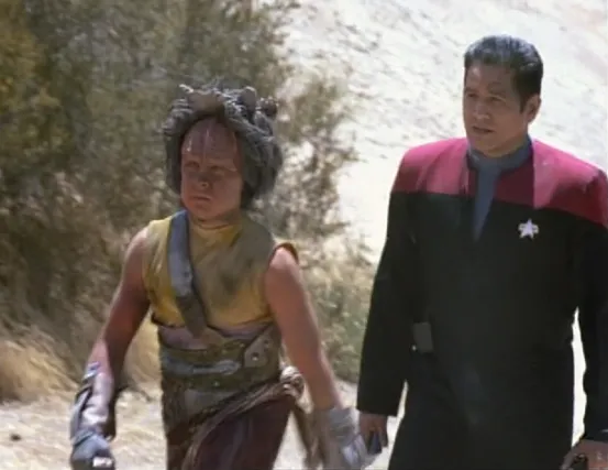 Chakotay follows a young Kazon man on a rocky planet surface