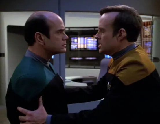 A concerned Reginald Barclay holding the Doctor by his arms and looking him in the eye