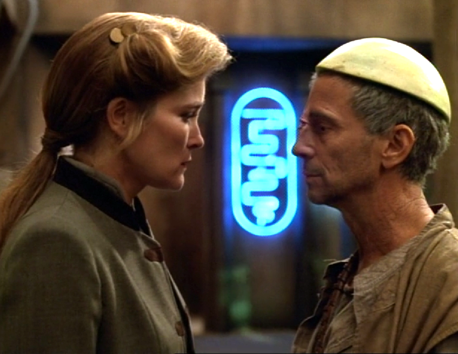 Janeway standing on a street with a man wearing a melon rind on his head