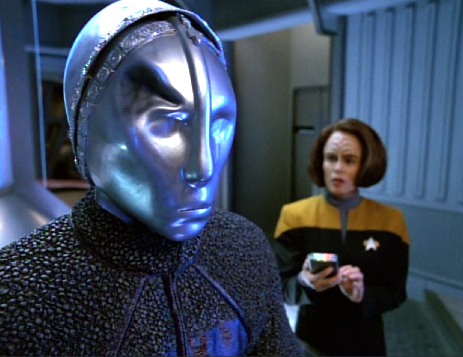 Torres looking at a silver-colored humanoid robot with a dent in its head