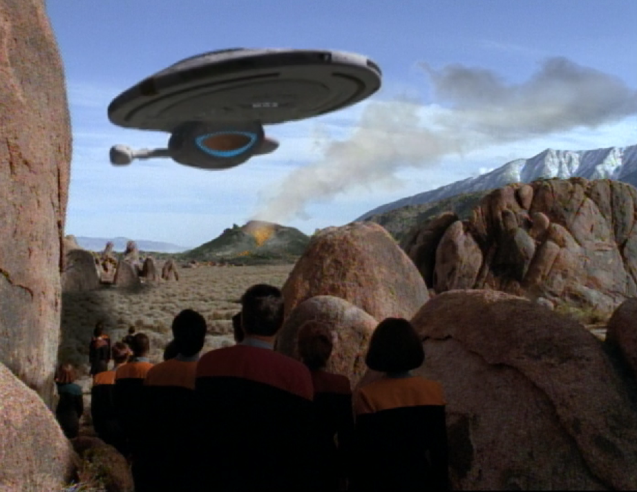 Members of the Voyager crew on the surface of a volcanically-active planet watching as the USS Voyager takes off and leaves orbit
