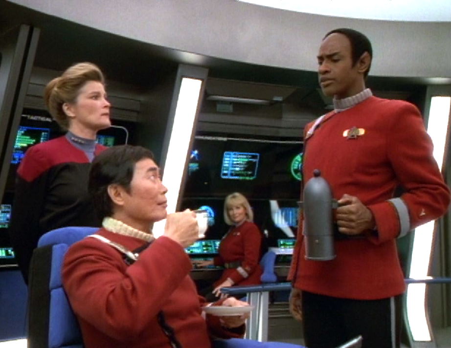 Tuvok, wearing a 2380s-style Starfleet uniform, serving tea to Captain Sulu while Janeway and Janice Rand observe