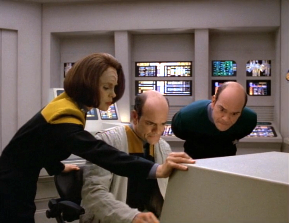 B'Elanna, the Doctor, and a man who look just like the Doctor looking over a computer screen
