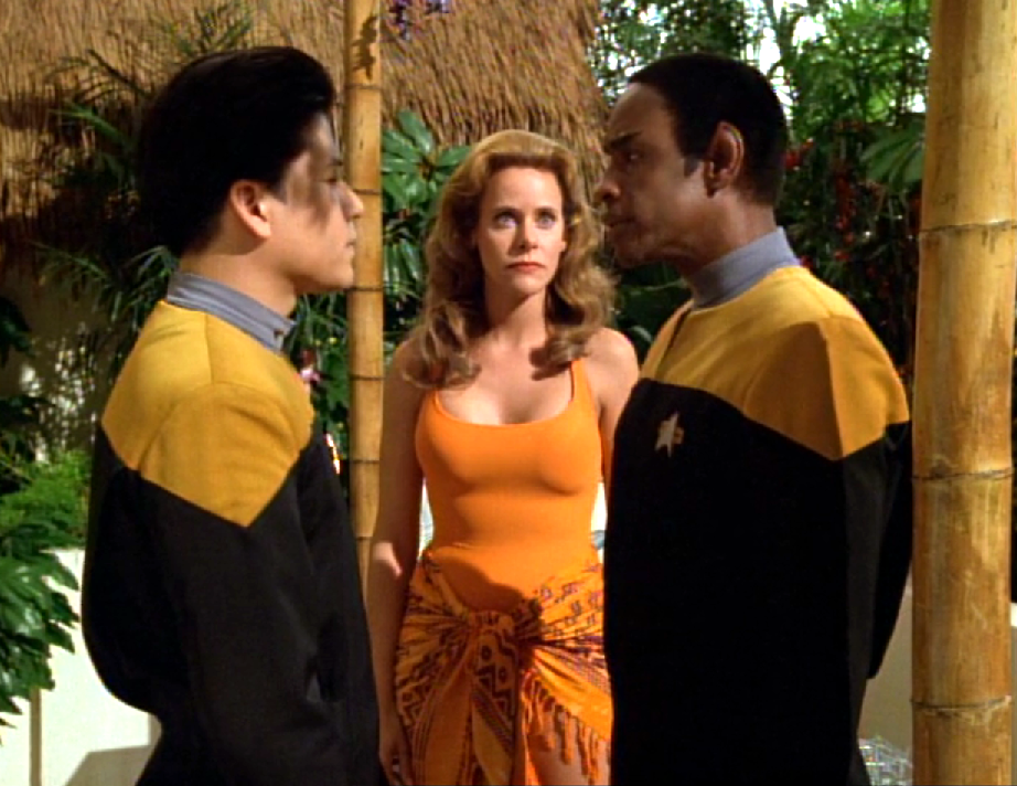 Kim and Tuvok speaking in front of a woman in a bathing suit