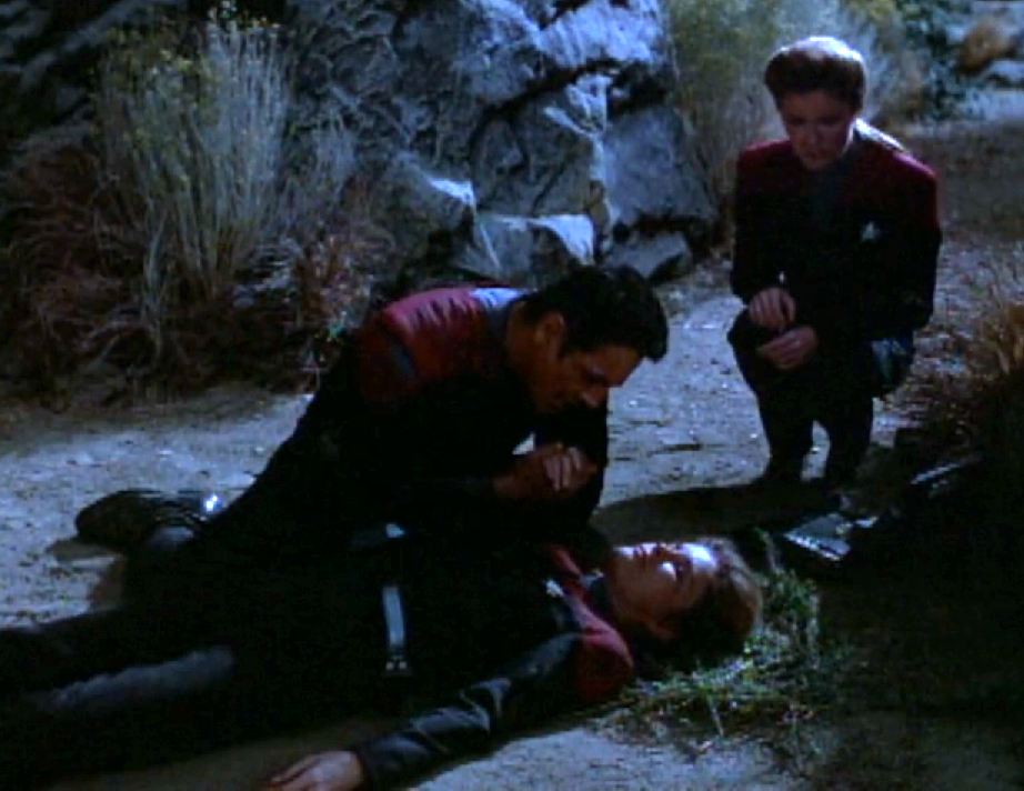 Chakotay kneeling over an unconscious Janeway while a second Janeway observes