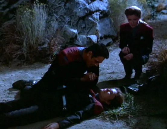 Chakotay kneeling over an unconscious Janeway while a second Janeway observes