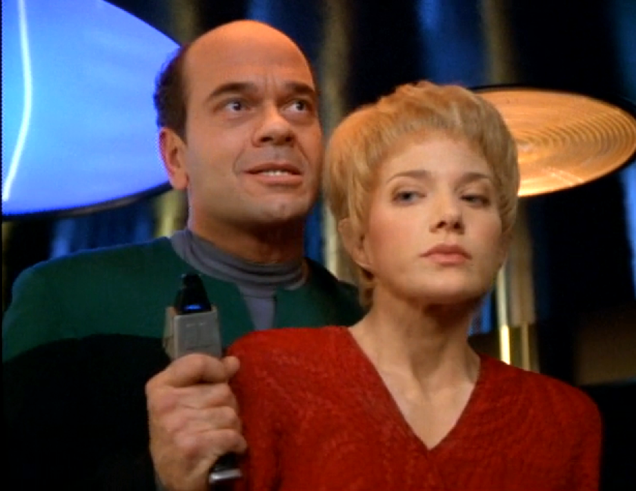 The Doctor holding Kes and a phaser on the transporter pad