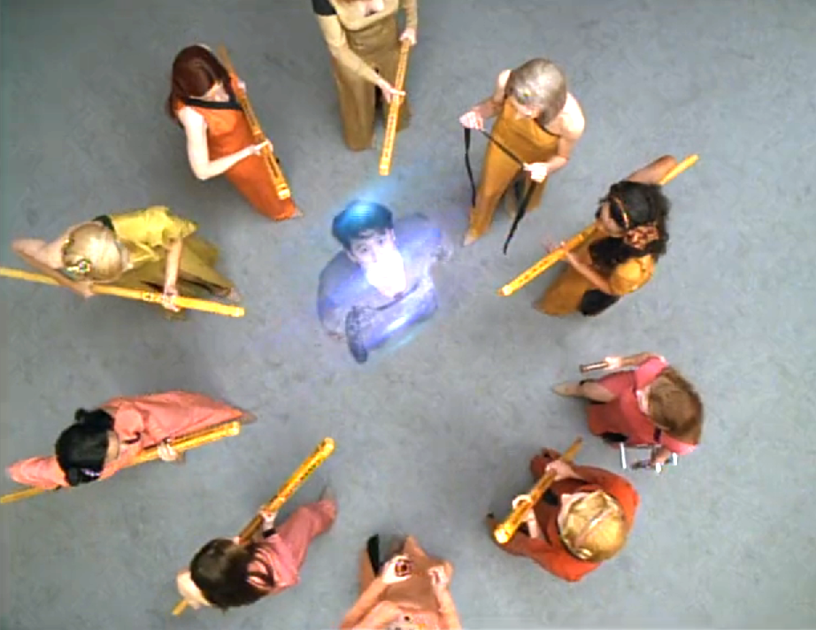 Kim being beamed up after being surrounded by ten women with staffs