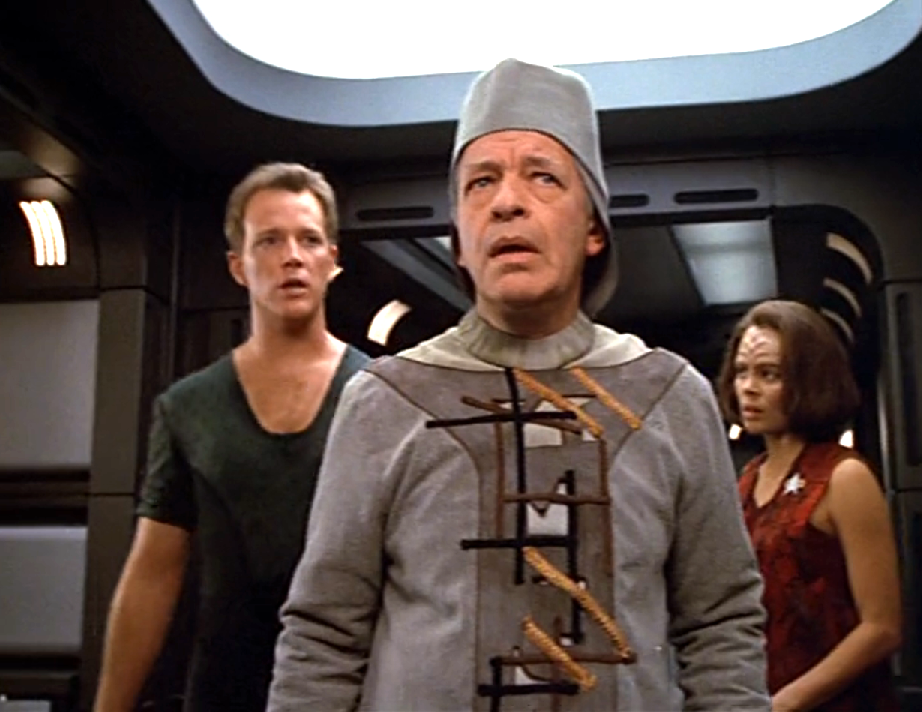 Tom, B'Elanna, and a confused looking man in one of Voyager's corridors