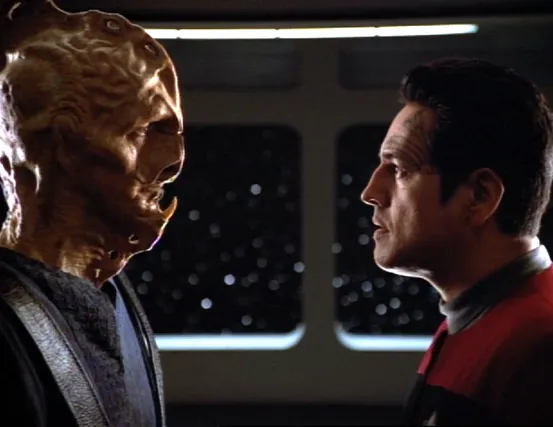 Chakotay facing an alien with a large head ridge and horn-like protrusion on his chin