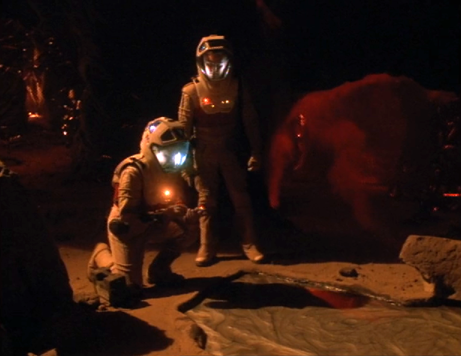 Tom Paris and Harry Kim in space suits scanning a pool of silver goo on a planet's surface