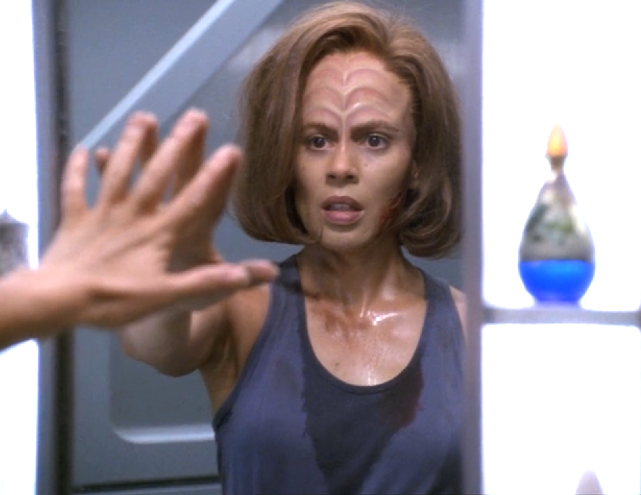 Torres, covered in dirt and sweat, reaching out to touch a mirror as she looks at her reflection