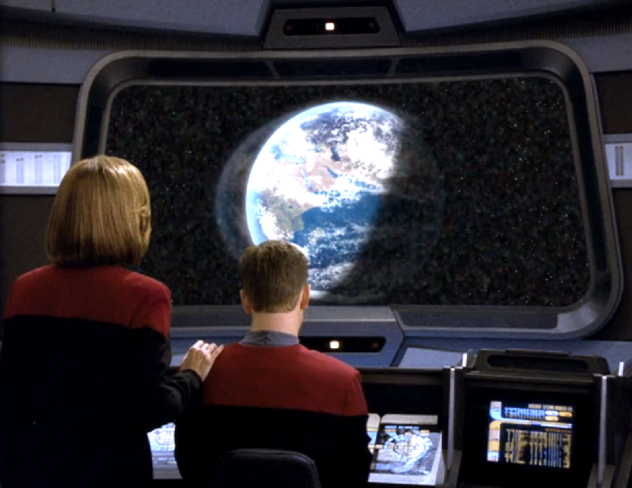 Janeway and Paris looking at the viewscreen, which is displaying a blurred image of Earth