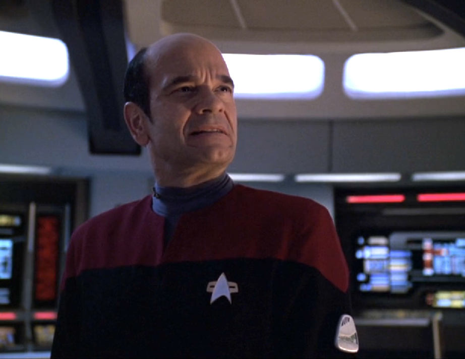 The Doctor wearing a red uniform and captain's pips on the bridge of Voyager