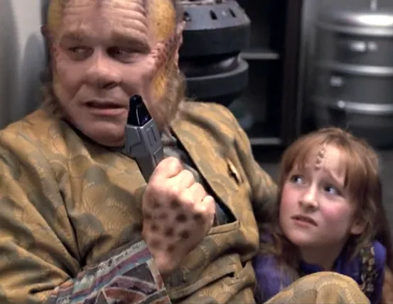 Neelix holding a phaser and hiding in the galley with a frightened-looking Naomi Wildman