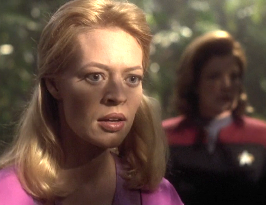 Seven of Nine, with no Borg implants and her hair let down, standing in a forest with Janeway nearby