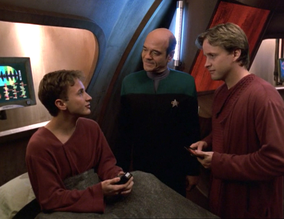 The Doctor and another man attending to a patient in an alien hospital