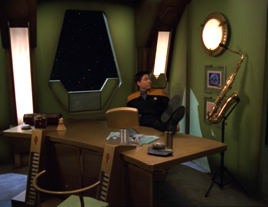 Harry Kim putting his feet up on the desk in an office adorned with personal effects, including his saxophone