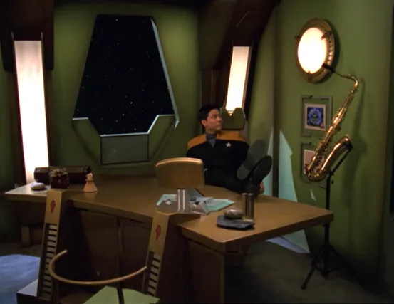 Harry Kim putting his feet up on the desk in an office adorned with personal effects, including his saxophone