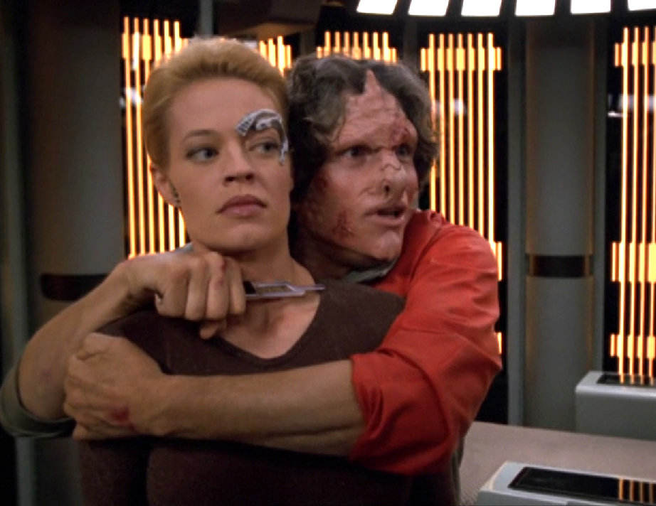 An alien man holding Seven of Nine hostage in sickbay with a sharp instrument held to her throat