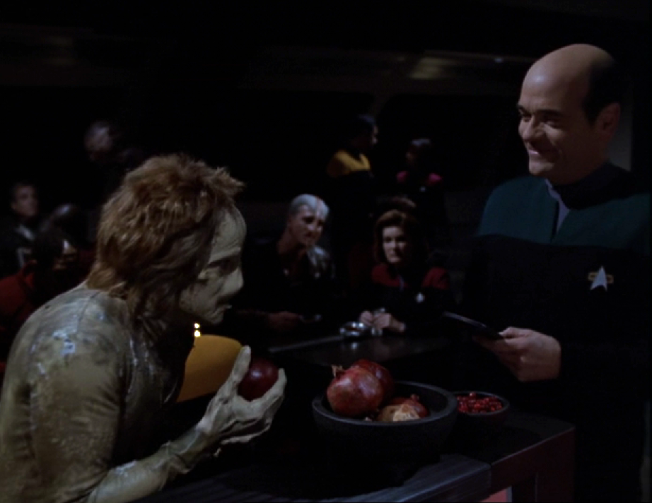 The Doctor speaking with an alien named Fantome while Janeway and a different alien watch in a darkened mess hall