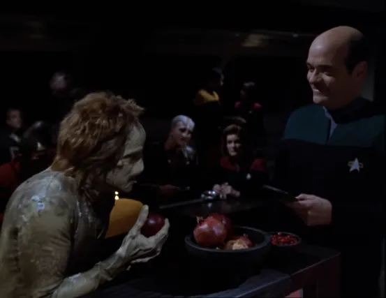 The Doctor speaking with an alien named Fantome while Janeway and a different alien watch in a darkened mess hall