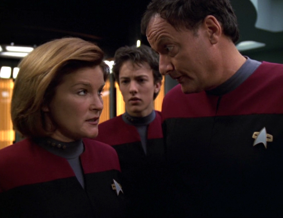 Janeway and Q have a conversation while Q's son watches, concerned