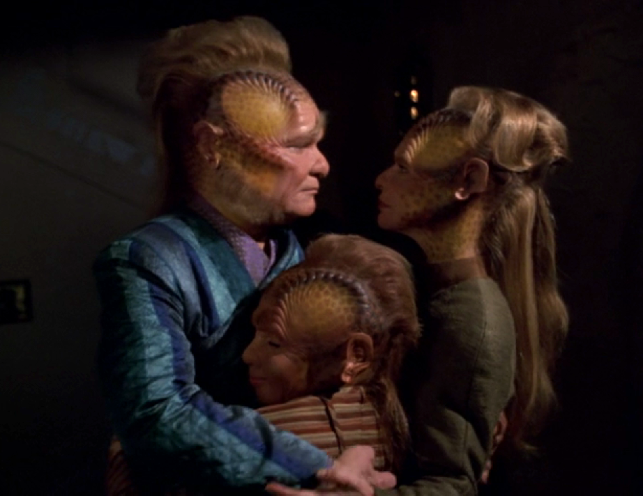 Neelix embracing a Talaxian woman and her son